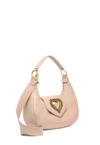 Borsa a tracolla beige in pelle con forma curva. Presenta una chiusura a gancio a forma di cuore dorato e una tracolla rimovibile. Texture liscia e design minimalista.