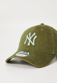 Zöld kordbársony sapka állítható pánttal, kiemelkedő világoskék "NY" logóval és egy kör alakú címkével, amelyen az áll "9FORTY ADJUSTABLE."