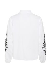 White shirt with long sleeves, featuring black floral embroidery on the sleeves. Classic collar and button closure at the back.