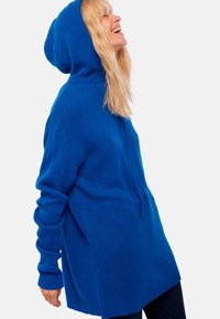 Helles blaues Kapuzensweatshirt aus softem Strickmaterial, mit langen Ärmeln und lockerer Passform sowie gerippten Bündchen und Saum.