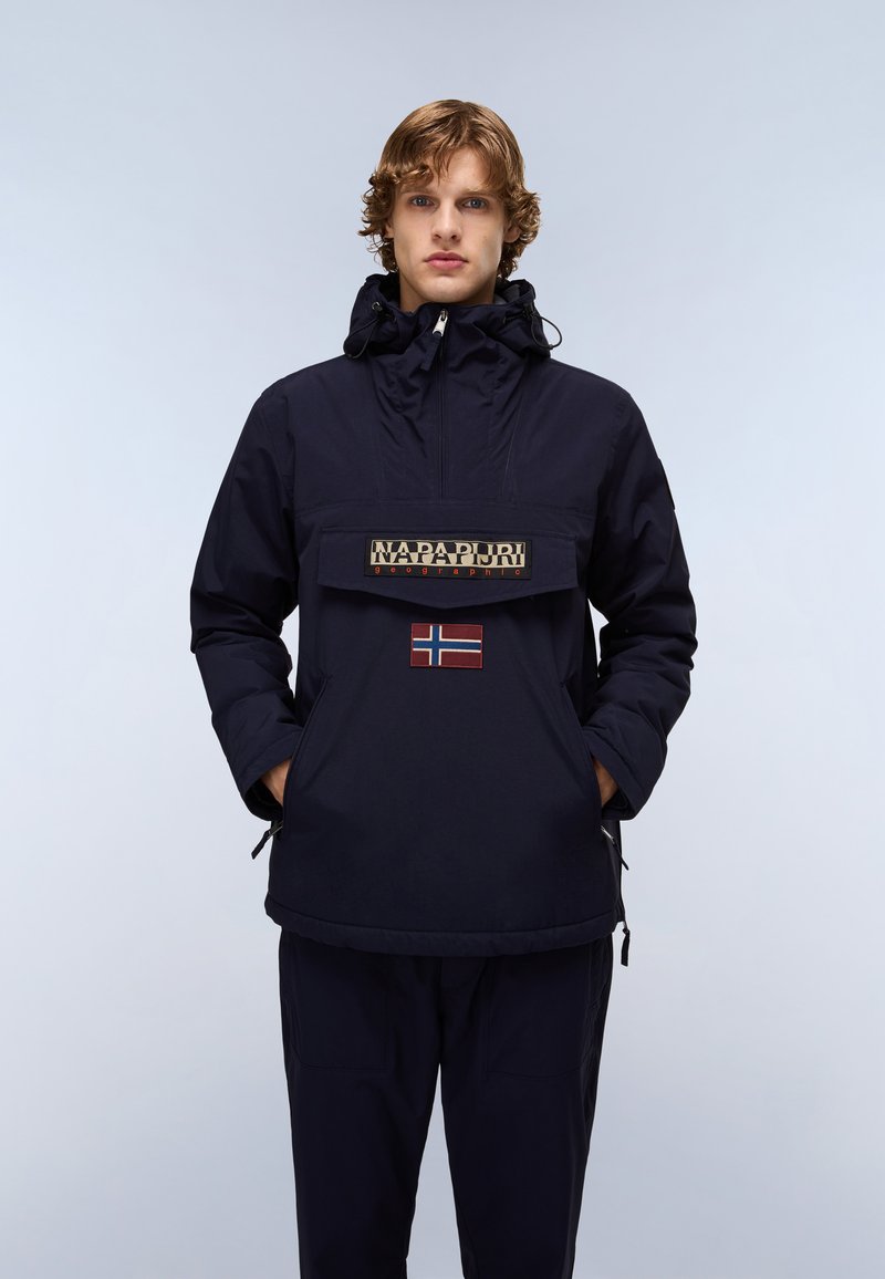 Navy blue anorak with a front pocket, featuring a logo patch and a Norwegian flag. Made of water-resistant material, it has a drawstring hood.