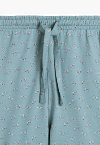 Jasnoniebieskie spodnie dresowe z elastycznym pasem i sznurkiem do regulacji, z powtarzającym się wzorem małych, białych motyli.
