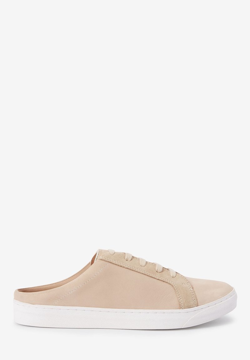 Chaussure en cuir beige à enfiler avec une texture lisse, devant à lacets et semelle en caoutchouc blanche. Présente un bout arrondi et des accents de design subtils.