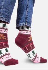 Czerwono-bia�łe skarpetki w wzory z piernikami, bałwankami i choinkami, wykonane z miękkiego materiału, zapewniające przytulne dopasowanie.