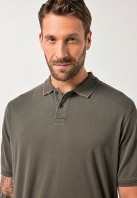 Tmavě olivově zelené polo tričko, krátké rukávy, klasický límeček, dvouknoflíková léga, texturovaná tkanina s jemnými švy.