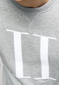 Szara bluza z nadrukiem "II" w kolorze białym, z prążkowanym dekoltem i miękką fakturą. Prezentuje swobodny, sportowy styl.