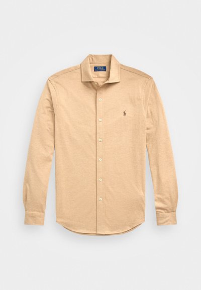 Beige langermet skjorte med knappestopp laget av mykt stoff, med klassisk krage, tonalt søm og en liten logo på venstre bryst.