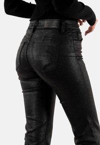 Jeans in denim nero scintillante con vestibilità slim, design a cinque tasche e un'etichetta in pelle sulla vita posteriore.