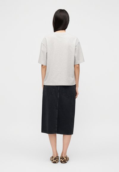 Γκρι φαρδιά μπλούζα με κοντά μανίκια, συνδυασμένη με μακριά μαύρη τζιν φούστα με δύο πίσω τσέπες και παπούτσια με λεοπάρ σχέδιο.