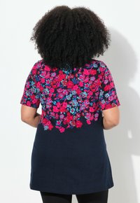 Túnica de manga corta con la parte inferior en azul marino y un vibrante patrón floral en rosa y azul en la parte superior. Tejido suave con un corte ligeramente holgado.