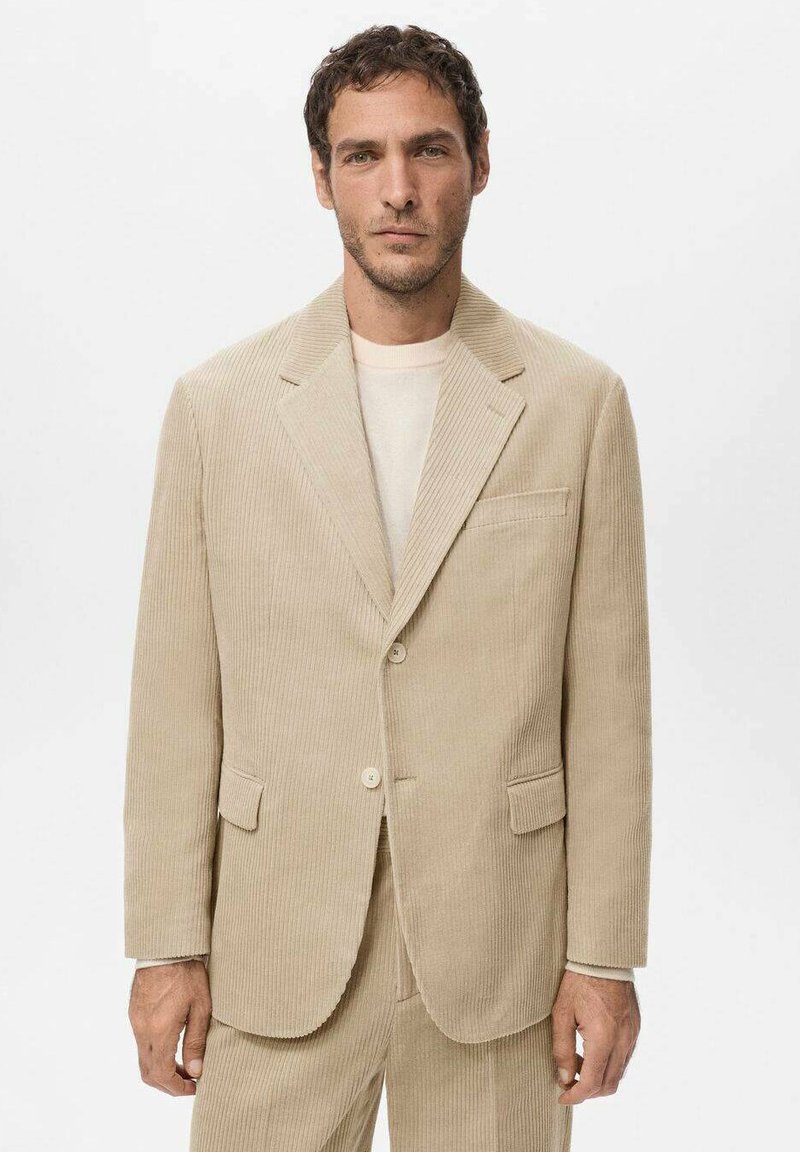 Beige corduroy blazer with a notched collar, two front pockets, and a single button closure. Textured fabric adds visual interest.