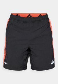 Shorts de sport noirs avec des panneaux latéraux orange, taille élastique et logo Adidas réfléchissant sur la jambe droite, étiquette Climacool sur la gauche.
