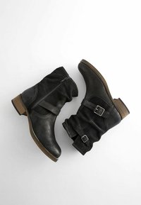 Stivaletti neri in pelle con design arricciato, chiusura con zip e fasce laterali con fibbie. Tacco impilato effetto legno.