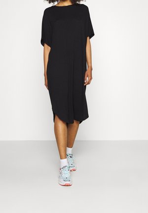 Sort oversized T-shirt-kjole med rund hals, korte ærmer og sideslidser. Bæres med lyseblå atletiksko med farverige detaljer.