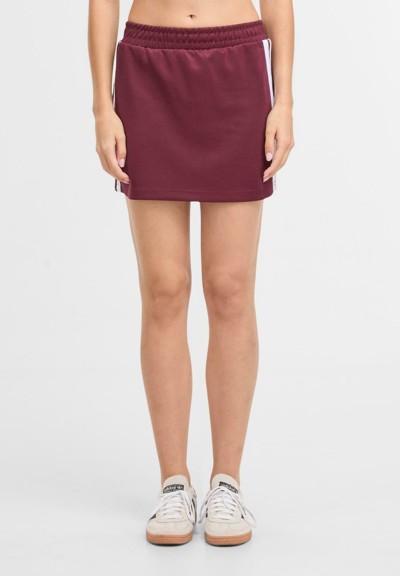 Gonna sportiva maroon con elastico in vita, di lunghezza corta e strisce bianche laterali. Realizzata in tessuto morbido per comfort e flessibilità.
