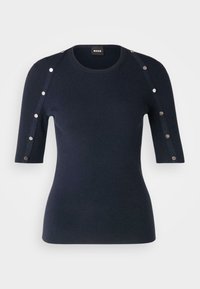 Tmavě modrý žebrovaný pletený top s krátkými rukávy, ozdobený kovovými cvočky podél ramene a s kulatým výstřihem.