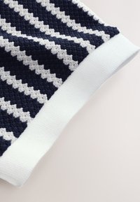 Gestrickter Pulloverstoff in Marineblau und Weiß mit Streifenmuster und strukturierter Oberfläche. Die Bündchen sind mit einem glatten weißen Rippstrick versehen.
