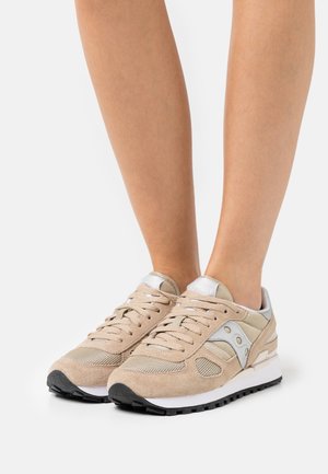 Béžové semišové a síťované tenisky se stříbrným akcentem a bílou podrážkou. Mají viditelné tkaničky a strukturované panely. Gumová podrážka pro lepší přilnavost.