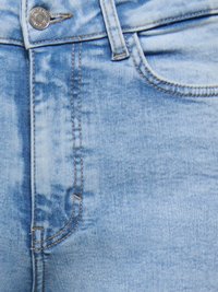 Vaqueros de mezclilla azul claro con cierre de botones, bolsillos frontales y detalles de costura visibles, con una textura ligeramente descolorida.