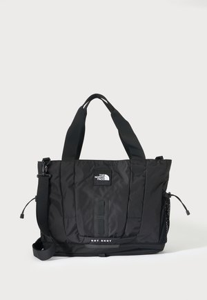 Sac tote noir The North Face avec deux poignées, bandoulière réglable, poche latérale en mesh et texte "HOT SHOT" en bas à l'avant.