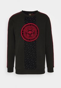 Felpa nera con piping rosso sulle maniche, pannello verticale centrale decorato e un emblema circolare rosso con un'ape coronata e del testo.