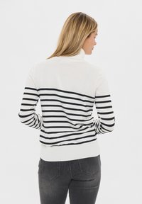 Sweter typu golf w kolorze kość słoniowa i czarni, z poziomymi paskami na plecach, dopasowany krój oraz ściągacze na dole i przy mankietach.