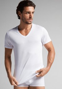 Witte kortekleurige t-shirt met v-hals, gemaakt van soepel katoen, aansluitend ontwerp, gedragen met bijpassende witte boxershorts. Eenvoudige, schone esthetiek.