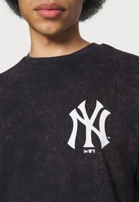 Černé tričko s tie-dye vzorem z bavlny, kulatým výstřihem. Na hrudi se nachází bílé vyšívané logo New York Yankees.