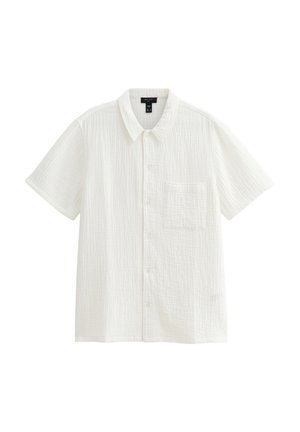 Chemise blanche à manches courtes en tissu texturé. Elle présente un devant à boutons et une poche poitrine unique. Design épuré et simple.