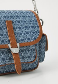 Borsa a mano in tessuto blu con motivo e dettagli in pelle marrone. Caratterizzata da una chiusura in metallo argentato e una tracolla a catena. Forma rettangolare compatta.
