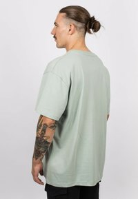 Light green cotton t-shirt with short sleeves, a relaxed fit, and a crew neck, featuring a smooth texture and minimal design.
