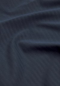 Tmavomodrá látka s hladkým povrchom, s jemnými diagonálnymi prúžkami. Materiál je ľahký a mierne elastický.