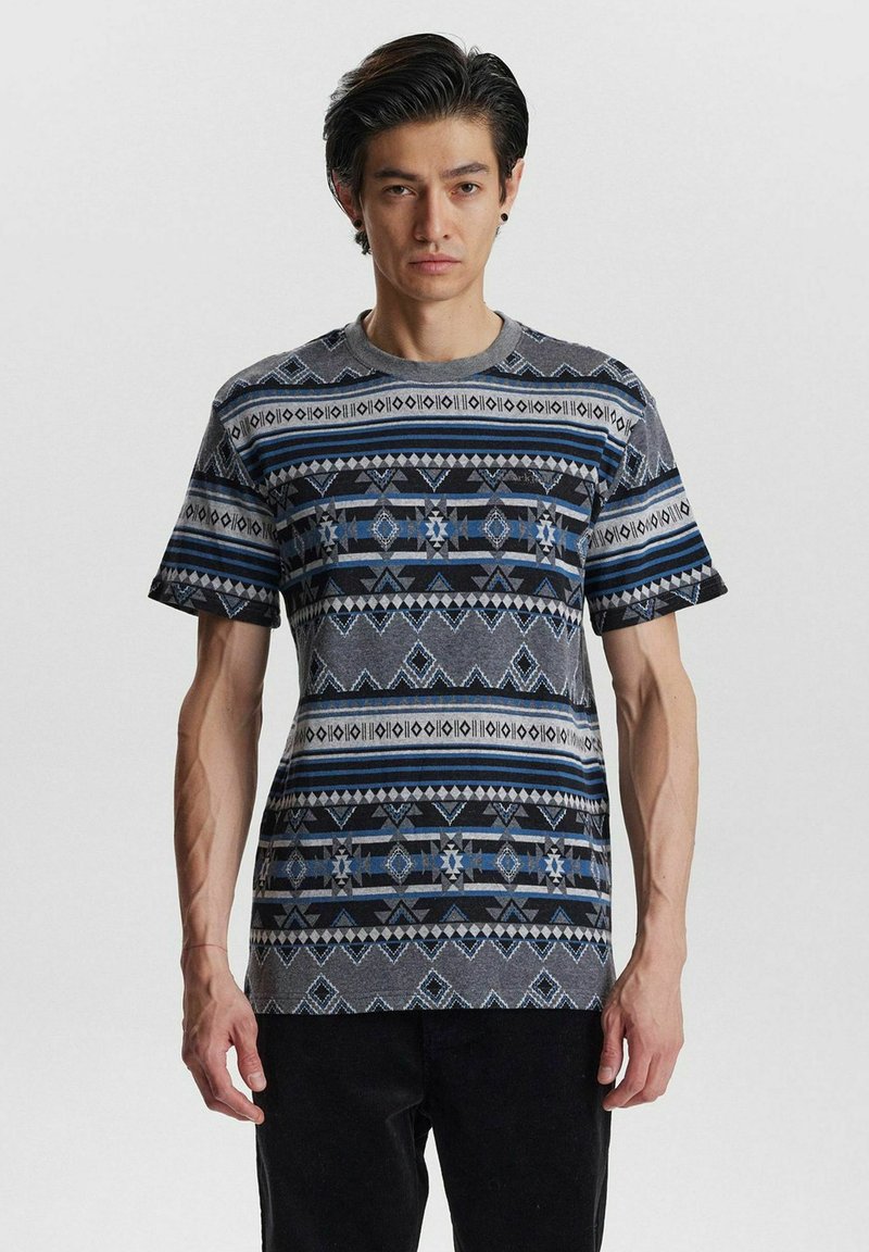 Camiseta de manga corta con patrón en gris, que presenta diseños geométricos en azul y negro y un escote redondo. Fabricada con un material suave y ligero.