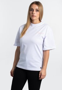 White short-sleeve t-shirt made of cotton, featuring a pink embroidered text on the chest and a small logo tag on the bottom left side.