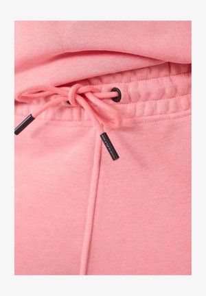 Pantalon de jogging rose avec taille élastique et cordon de serrage, doté d'aglets noirs et d'un tissu doux et texturé. Poignets élastiqués aux chevilles.