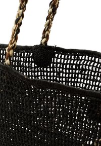 Cesta tejida negra hecha de fibras naturales, con asas trenzadas en tonos negro, blanco y marrón. Estructura abierta con base circular.