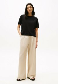 Sort kortærmet T-shirt med rund halsudskæring, parret med beige, bredbenede bukser. Outfittet har en afslappet pasform for komfort.