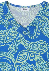 Tissu bleu avec motif cachemire vert clair et encolure en V, montrant une étiquette de vêtement blanche avec le texte "CECIL" au col.