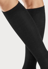 Schwarze knielange Socken aus glattem Stoff mit gerippten Bündchen, die einen engen Sitz und ein minimalistisches Design zeigen.