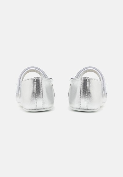 Zapatos de bebé de cuero plateado con aberturas traseras y recortes curvados, que presentan una textura suave y costuras reforzadas a lo largo de los bordes.