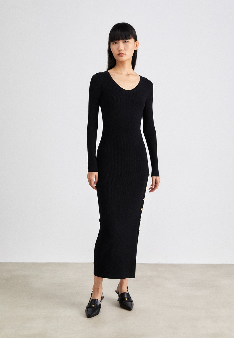 Black ribbed long-sleeve dress with a deep V-neck and side buttons. The dress has a fitted silhouette and reaches mid-calf.