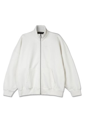 White zip-up sweatshirt made of soft fabric, featuring a high collar, large pockets, and a relaxed fit. Subtle branding on the chest.