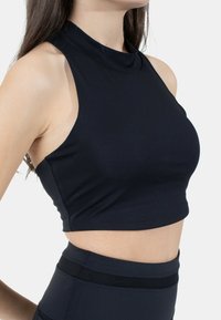 Top corto senza maniche di colore nero con un collo alto, realizzato in un materiale liscio e elasticizzato, caratterizzato da ampie aperture per le braccia e un busto aderente.