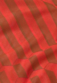 Tekstureret stof med skiftevis røde og brune striber i et geometrisk mønster, der udviser en bølgeformet overflade og en subtil glans.