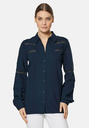 Navy blue button-up shirt featuring lace inserts, vertical pleats, and long sleeves. Made of lightweight fabric with a soft texture.