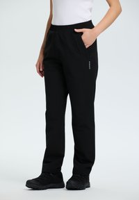 Zwarte stretchbroek met een elastische tailleband, zijzakken en een ritszak, gemaakt van een gladde, duurzame stof.