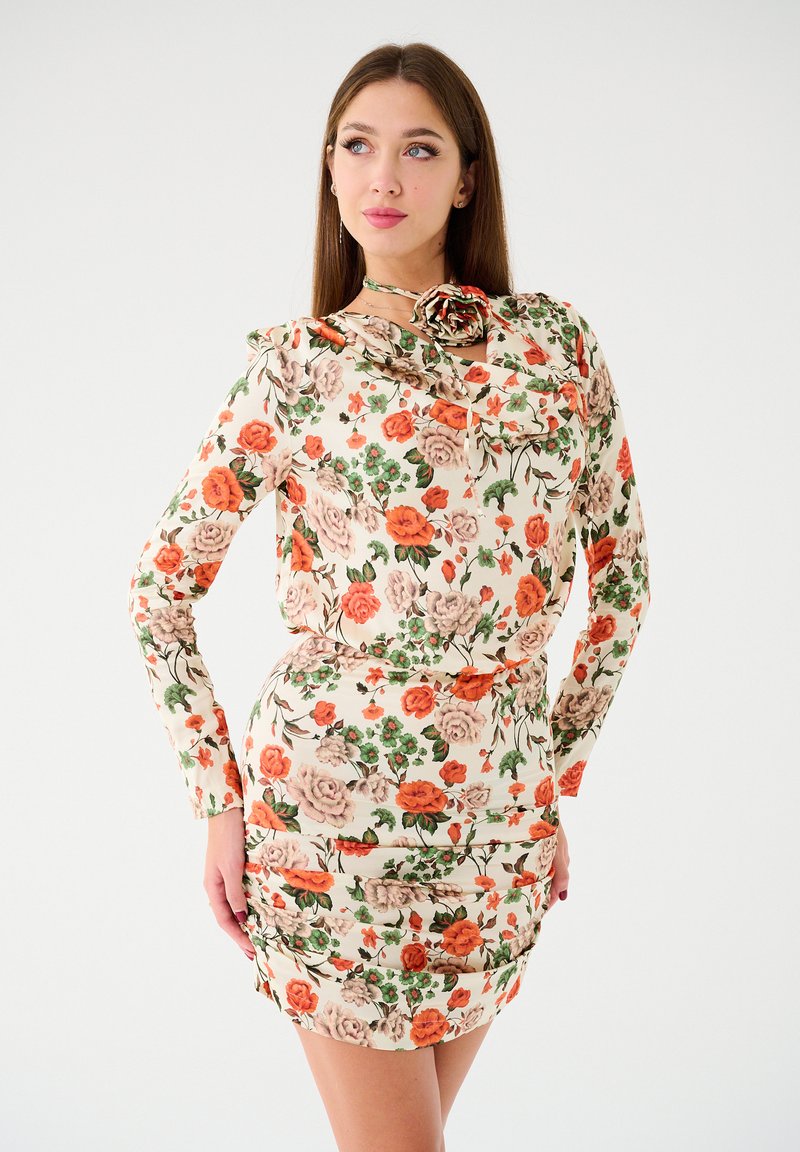 Kwiatowa mini sukienka z długimi rękawami, z kremowym tłem oraz czerwonymi, różowymi i zielonymi różami. Materiał ma gładką teksturę i marszczony design.