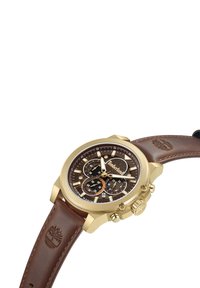 Orologio cronografo dorato con quadrante marrone, cinturino in pelle marrone e cassa testurizzata. Presenta sottocassette e un dettaglio del logo.