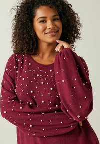 Pull bordeaux à manches bouffantes, orné de perles éparpillées sur le tissu texturé. Conception à col rond.