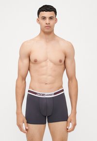 Boxer in grigio con elastico a strisce bianche e borgogna, con il nome del marchio "JACK & JONES" stampato sul davanti.